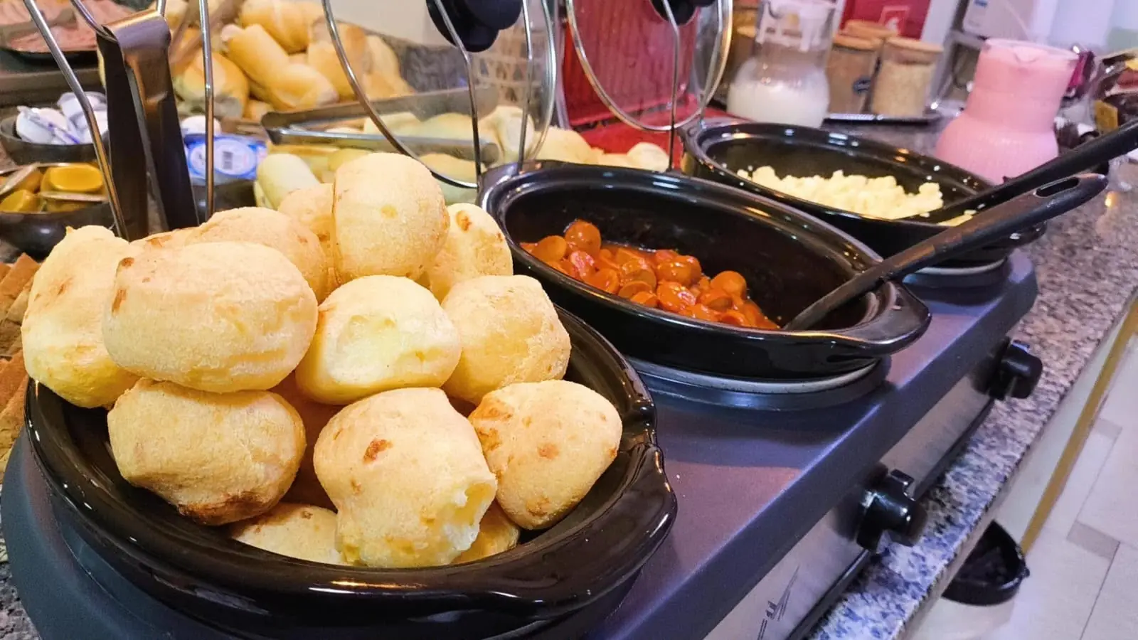 Pão de queijo e ovos mexidos no buffet quente